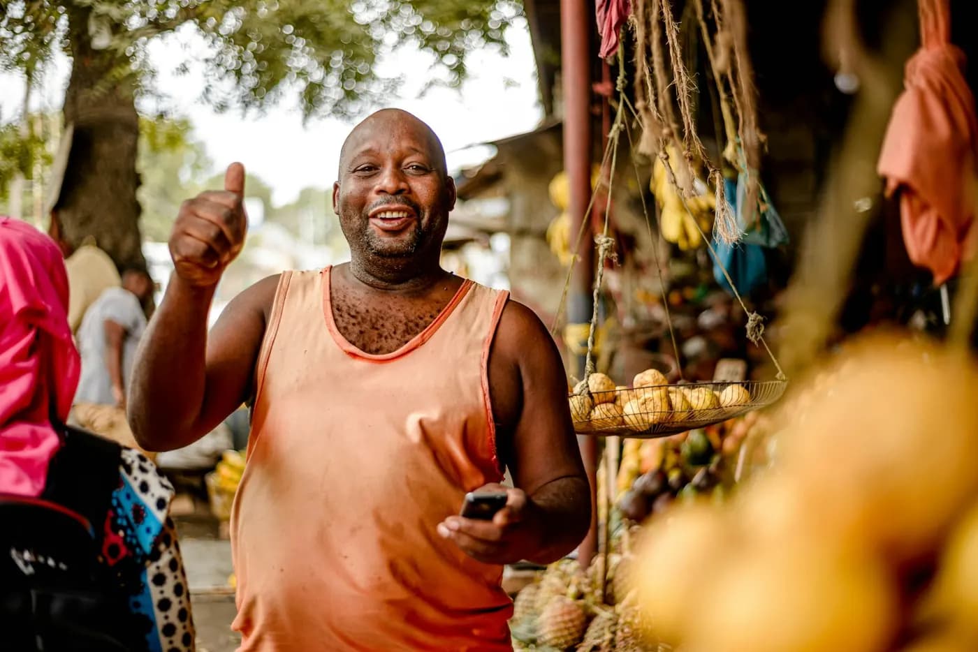 Smiling market trader holding his phone at a produce stall